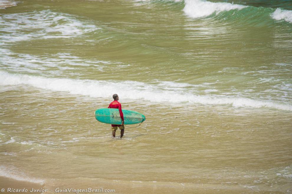 Imagem de um surfista entrando no mar.